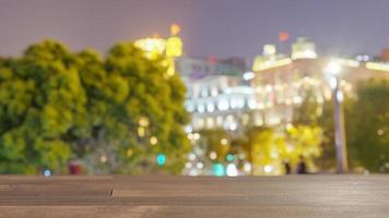 Wood table top on blur buildings in the night city background. For montage product display or key visual layout. photo