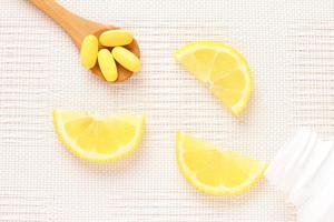 Yellow vitamins on spoon and lemon slices as a background photo