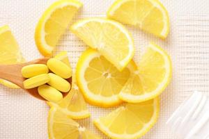 Yellow vitamins on spoon and lemon slices as a background photo