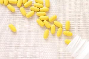 píldoras amarillas vitaminas, montón de tabletas en mesa blanca