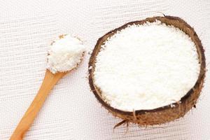 Coconut flakes in coconut shell and wooden spoon, natural ingredients photo