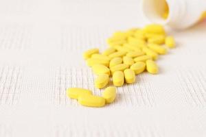 Yellow pills vitamins, bunch of tablets on white table