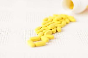 Yellow pills vitamins, bunch of tablets on white table