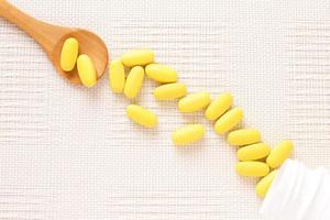 Yellow pills vitamins, bunch of tablets on white table photo