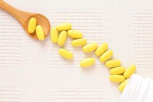 Yellow pills vitamins, bunch of tablets on white table photo