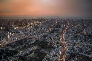 Panoramic Osaka cityscape in orange sky twilight time, with street, movement light, building and landmark. photo