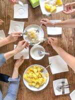 Top view of many people scoop the Thai traditional dessert mango and sticky rice on the wood table. photo