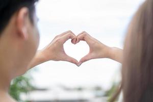 groom and bride coordinate their hand together for create HEART shape with the clear sky photo