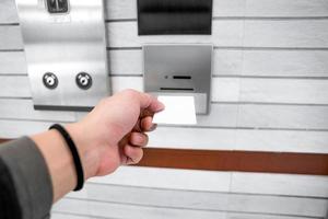 securing lift or elevator access control, man's hand is holding a key card lay up to insert in card hold for unlocking elevator doors before up or down. photo