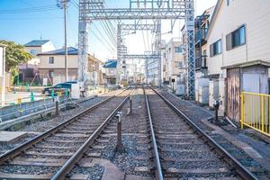 vías de ferrocarril japonesas locales con estacionamiento para el hogar y el automóvil al lado foto
