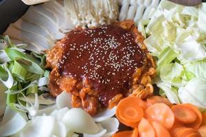 tokboki comida tradicional coreana pastel de arroz caliente y picante, combinación y aplicación de hojaldre con queso y verduras en la mesa negra foto