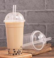 Takeout with disposable item concept popular Taiwan drink bubble milk tea with plastic cup and straw on wooden table background, close up, copy space