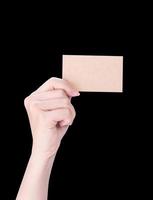 mano de niña limpia de asia joven sosteniendo una plantilla de tarjeta de papel marrón kraft en blanco aislada en fondo negro, ruta de recorte, cierre, maqueta, corte foto