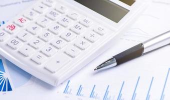 White calculator and report with chart and graph, concept of annual financial profit overview, banking and investment, copy space, macro, close up photo