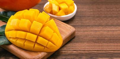 Fresh Mango - Juicy chopped mango cubes on wooden cutting board and rustic timber background. Tropical summer concept. Close up, macro, copy space. photo