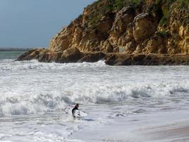 albufeira, sur del algarve, portugal, 2018. vista de un surfista en la playa de albufeira en portugal el 10 de marzo de 2018. persona no identificada foto