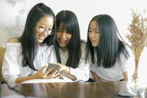 grupo de adolescentes asiáticos leyendo mensajes en teléfonos inteligentes foto