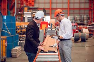 Factory worker foreman and engineer manager working together at industrial worksite , wearing hard hat for safety photo