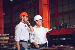 Factory worker foreman and engineer manager working together at industrial worksite , wearing hard hat for safety photo