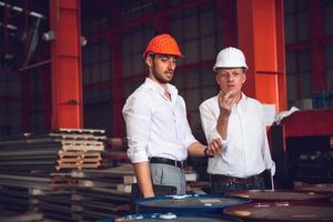 Factory worker foreman and engineer manager working together at industrial worksite , wearing hard hat for safety photo