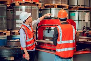 Factory worker foreman and engineer manager working together at industrial worksite , wearing hard hat for safety photo