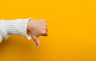 I don't like hands showing disapproving gestures thumb pointing down dissatisfied, reject, dislike Hand showing sign on yellow background in photo studio