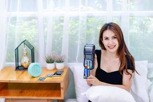 Woman and credit card With a credit card swipe machine in the bed, the concept of running an online business all the time photo