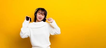 music listening to music Beautiful Asian woman in headphones listening to music and enjoying the sound of music. on a yellow background photo