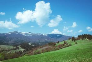 Landscape of the hill with haystacks in the great mountains in spring in the cloudy day photo