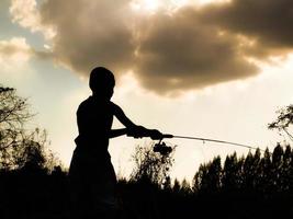 silueta de un niño pescando el tiempo feliz de los niños en medio de la naturaleza al atardecer