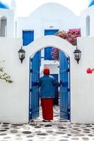 La parte trasera de la mujer musulmana abre la puerta de la casa tradicional de Grecia en Santorini foto