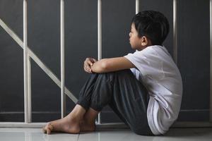 A young boy sitting alone with a sad feeling at home photo