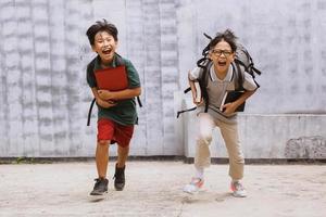 dos estudiantes asiáticos emocionados dan la bienvenida a la escuela después de la pandemia