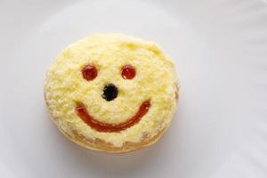 donut sonriente en plato blanco foto