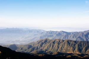 Mountain landscape in the fog with clear blue sky. photo