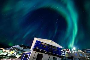 hermosa aurola luz del norte sobre el paisaje urbano de la ciudad. luces del norte en el sur de kitaa qaqortoq groenlandia foto