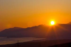 Sunset above hills on sea photo