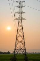el poste de electricidad en el campo durante la puesta de sol. foto