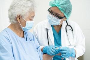 Doctor help Asian senior or elderly old lady woman patient wearing a face mask in hospital for protect safety infection and kill Covid 19 Coronavirus. photo