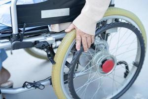 Paciente asiático mayor o anciano en silla de ruedas eléctrica con control remoto en la sala del hospital de enfermería, concepto médico fuerte y saludable foto