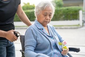 Caregiver help and care Asian senior or elderly old lady woman patient sitting on wheelchair at nursing hospital ward, healthy strong medical concept
