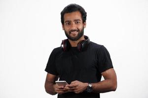 A Man is using mobile with headphones and happy in white background photo