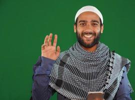 muslim boy saying hi on Green screen background. photo
