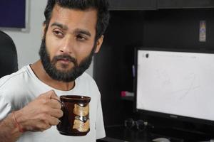 a man on computer table and having coffee cup photo
