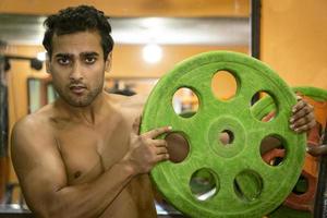 Young man in gym with gym plate going to lift weight photo