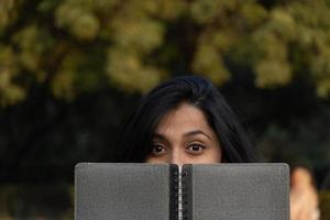 joven estudiante con diario cerca de sus ojos foto