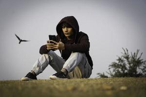 Young boy using mobile in Park High definition image photo