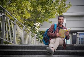 un joven estudiante universitario en el campus universitario tratando de leer su libro foto