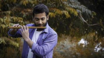 Flute player playing Flute During Autumn - Indian Handsome Flute Player Images photo