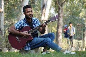 young boy with his guitar and playing guitar in park photo